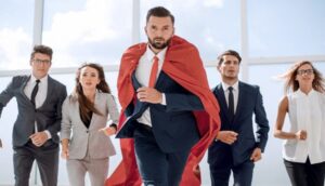man in suit with red cape depicting a hero runs ahead of the others
